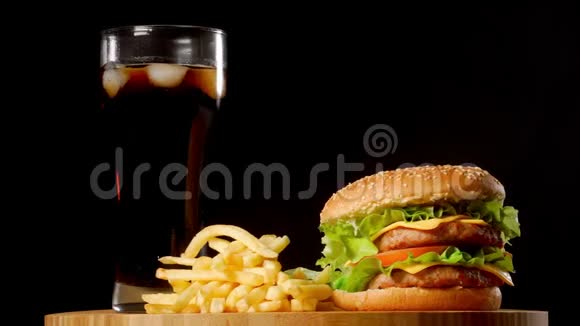 汉堡包配炸薯条和一杯冰可乐背景为黑色乡村风味视频的预览图
