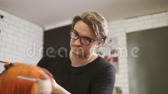 戴眼镜的时尚男理发师正在美容院剪红头发女人的头发一位年轻女子剪了头发视频的预览图