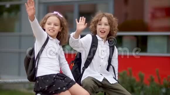 孩子们在挥手一个男孩和一个穿校服的女孩问候他们的同学回到学校视频的预览图