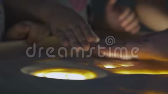 儿童和成人在灯光下的桌子上用沙子画画视频的预览图