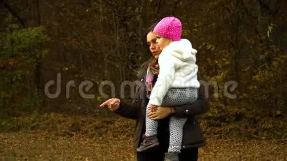 一位年轻的母亲和她的小女儿在秋天的森林里玩耍妈妈和女儿交流他们很开心视频的预览图