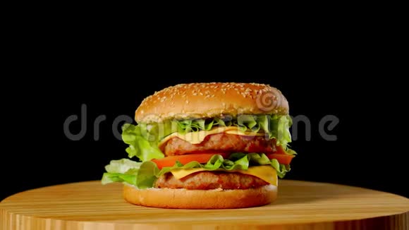 新鲜美味的汉堡在黑色背景上旋转无缝可循环射击4K视频的预览图