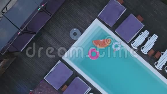 从游泳池顶部观看有明亮的彩色充气圆圈池顶上有五颜六色的景色视频的预览图