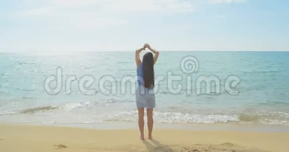 那个年轻女孩在海边的海滩上举手沙滩视频的预览图