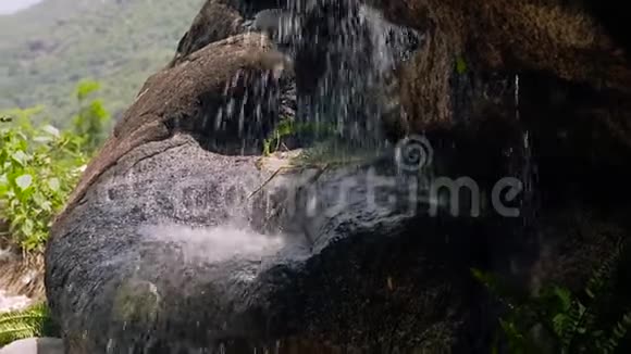 瀑布上的水流紧贴着石头从岩石中溅出的缓慢水流视频的预览图