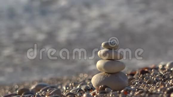 大海在海浪中翻越海滩上的小石头金字塔视频的预览图