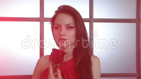 一个化妆鲜艳的年轻女孩手里拿着一朵红玫瑰视频的预览图