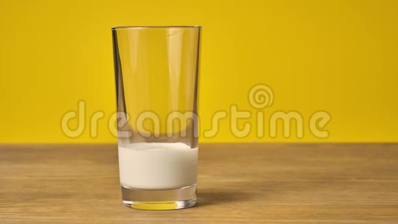 一叠饼干和一杯牛奶放在一张黄色背景的木桌上视频的预览图