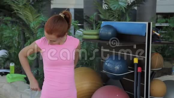 在豪华健身房里用带子测量腰部的女运动员的肖像视频的预览图