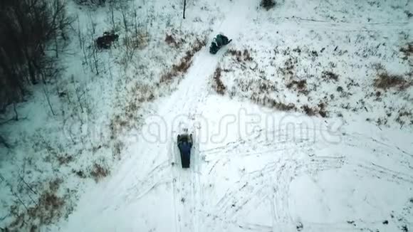 年轻人在冬天的森林里骑着雪地摩托直升机射击视频的预览图