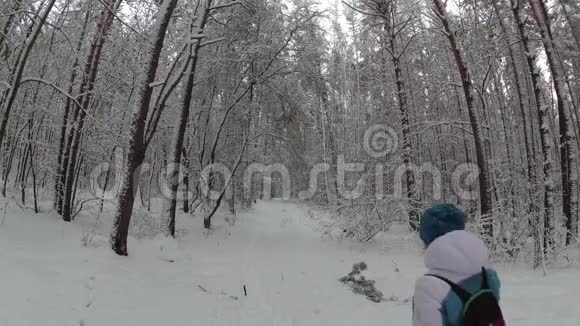 在冬日森林的小径上漫步的女人视频的预览图