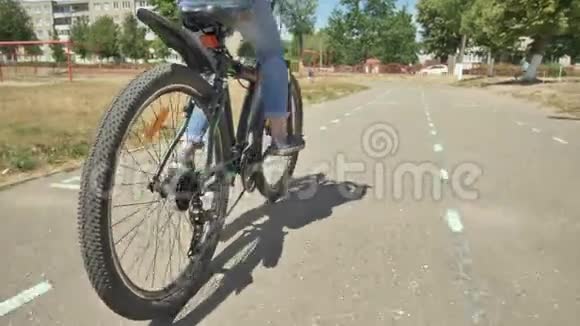 一个12岁的女孩在温暖的夏天骑自行车自行车轮靠近视频的预览图