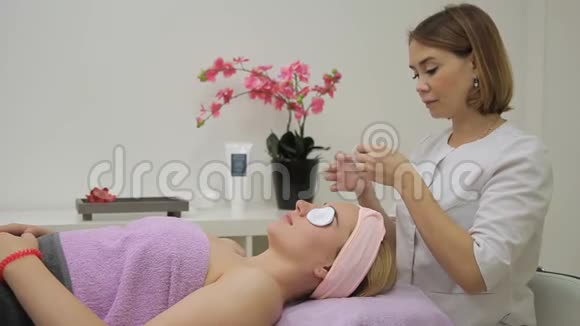 美容师用棉盘从女性脸上洗去眼妆视频的预览图