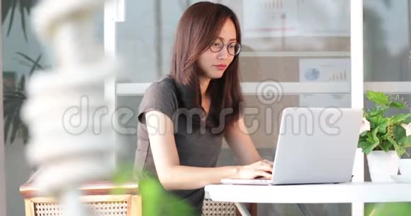 亚洲女人开始用她的笔记本电脑和手机工作视频的预览图