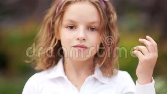 一个卷发和棕色眼睛的女孩的亲密肖像这孩子穿着一件白色衬衫挺直的头发视频的预览图