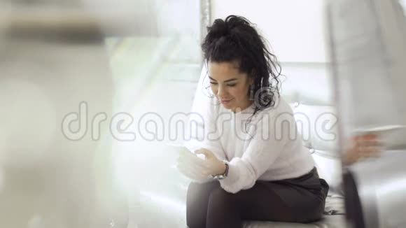 漂亮的女人坐在沙发上用智能手机视频的预览图