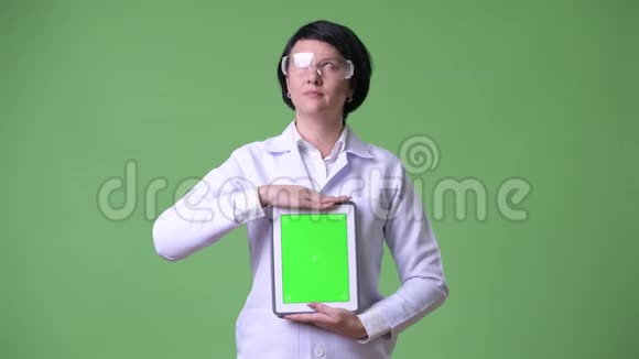 漂亮的女医生戴着防护眼镜显示数字平板电脑视频的预览图