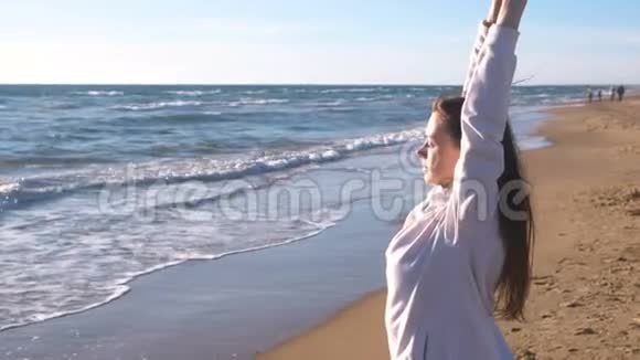 女人正在沙滩上伸展瑜伽海浪侧面观看视频的预览图