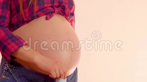 一个怀孕的女人在她赤裸的大肚子上带着可爱的新生袜子走路想让妈妈玩视频的预览图