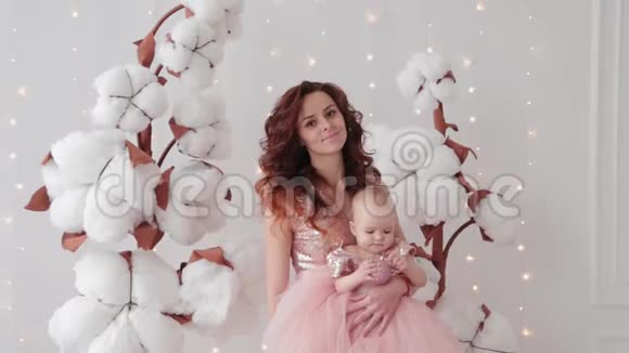 美丽的母亲和一个一岁的女儿在一个照相馆附近的人造棉花和发光墙视频的预览图