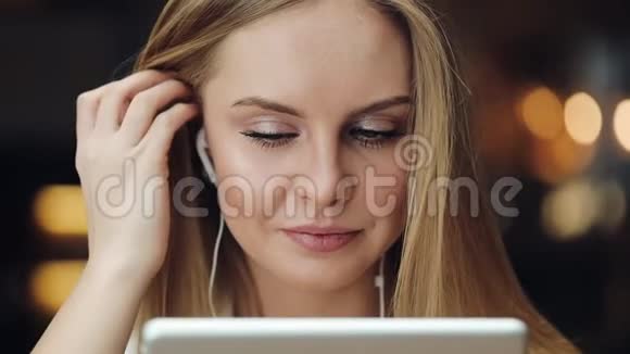 迷人的年轻女子微笑着用耳机里的平板电脑工作视频的预览图