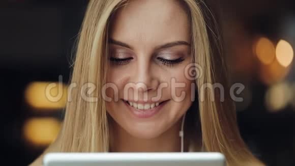 迷人的年轻女子微笑着用耳机里的平板电脑工作视频的预览图