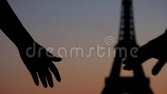 年轻的情侣携手来到巴黎埃菲尔铁塔前夕阳下的剪影视频的预览图