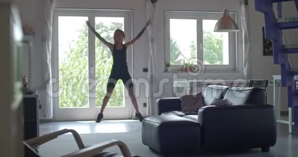 年轻的纹身女人在家庭健身运动中做跳跃式锻炼客厅家政培训4k视频的预览图