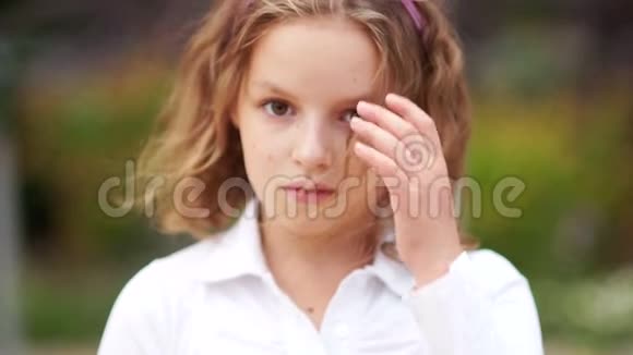 一个挑衅的少女从她脸上吹出一缕头发一个孩子穿着白色衬衫视频的预览图