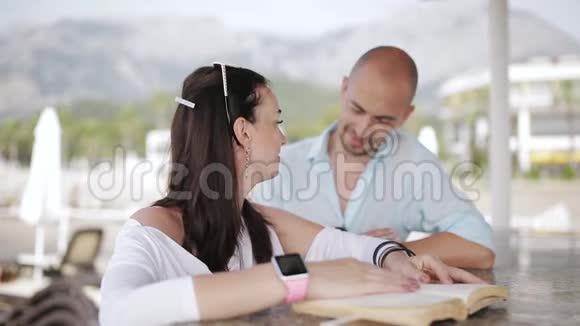 年轻夫妇在码头的酒吧调情年轻夫妇在你的电话里看照片在酒吧聊天视频的预览图