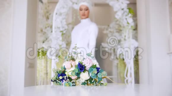 美丽的新娘穿着传统的穆斯林白色礼服束着鲜花视频的预览图