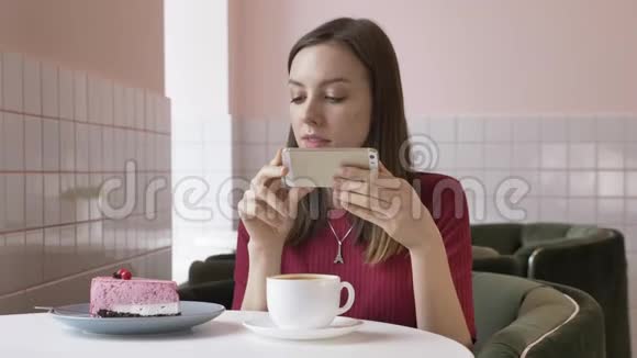 年轻漂亮的黑发女孩坐在咖啡馆里做蛋糕的照片今天的问题社交网络60英尺视频的预览图