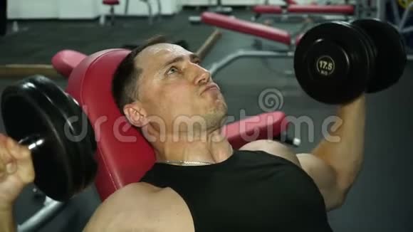 强壮的人在健身房里把重物举过头顶视频的预览图