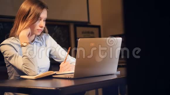 漂亮的女士坐在笔记本电脑前做笔记肖像高清视频的预览图