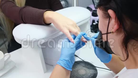 医生在美容院给顾客画指甲凝胶抛光漆器伪装钉子延伸视频的预览图