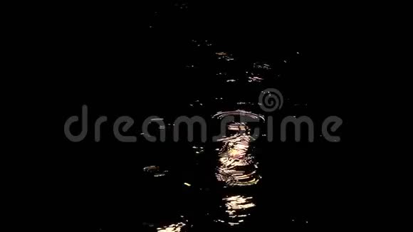 夜晚的雨滴穿过水坑水滴上的圆圈被路灯的光照亮自动视频的预览图