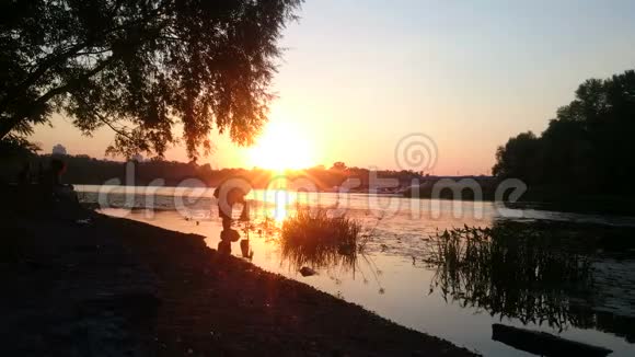 灵感摄影师站在河边日落时拿着相机美丽的自然视频的预览图