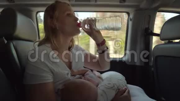 母亲在车里喝水和照顾婴儿视频的预览图