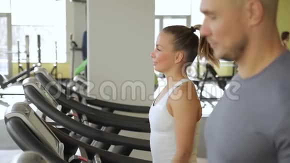 两个微笑的人改变了他们在健身房跑步机上跑步的步伐视频的预览图