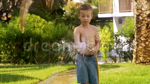 男孩在草坪上浇水然后弄湿了视频的预览图