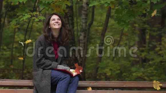 公园里落叶下快乐的年轻女子视频的预览图