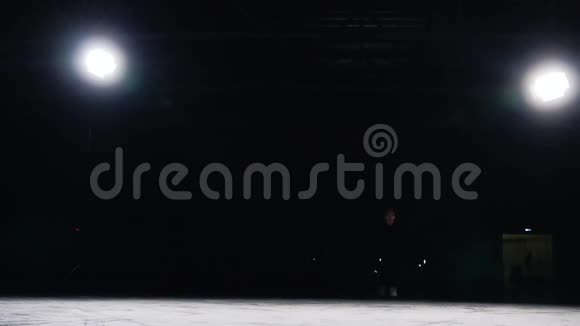 穿着黑色西装轮廓光线优美的溜冰者加速并突然停止冰鞋上的飞沙视频的预览图
