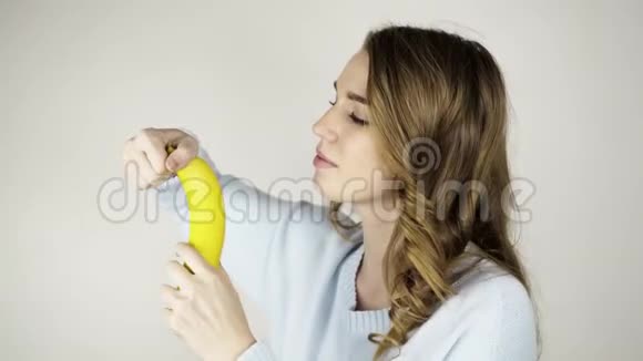 美丽的年轻女子剥着香蕉吃视频的预览图