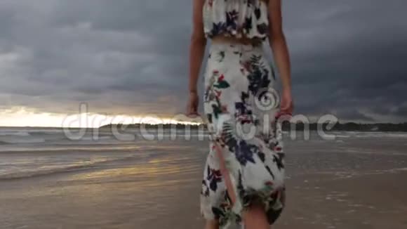 日落时分穿着裙子在海边散步的女孩视频的预览图