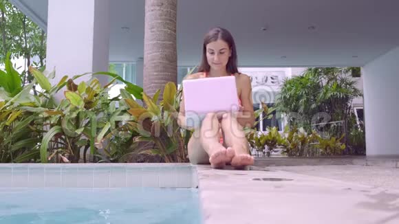 女自由职业者坐在游泳池旁在一台小型电脑上工作女孩把她的笔记本电脑扔进水里在忙期间视频的预览图