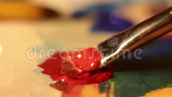 艺术家把刷子放在红色的油漆中然后把它混合在调色板上视频的预览图