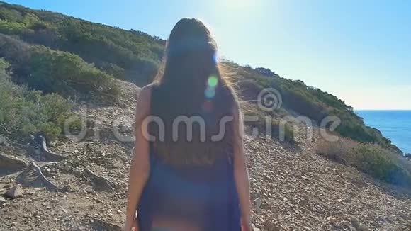 美丽的年轻女子在海边的荒山中散步慢动作视频的预览图