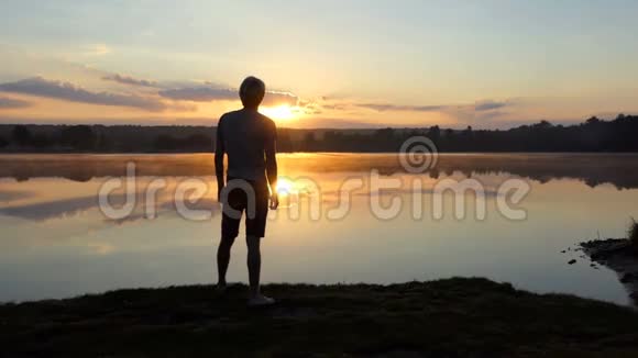 斯洛莫壮丽的日落时分年轻人举起拳头在湖面上挥舞视频的预览图