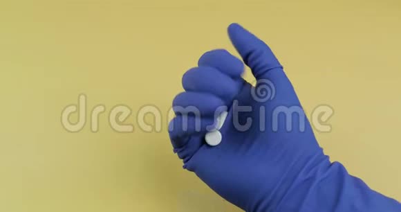 一个椭圆形和一个圆形的白色药片穿着蓝色的医用手套视频的预览图