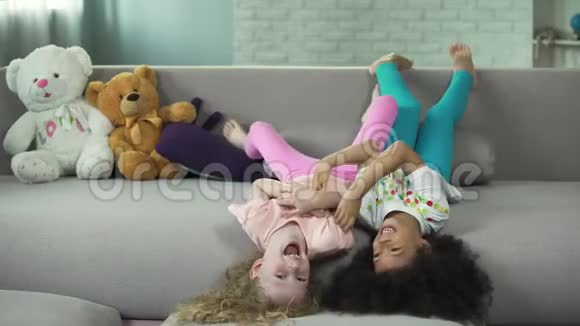 小的多种族儿童躺在沙发上在家里玩得开心童年视频的预览图